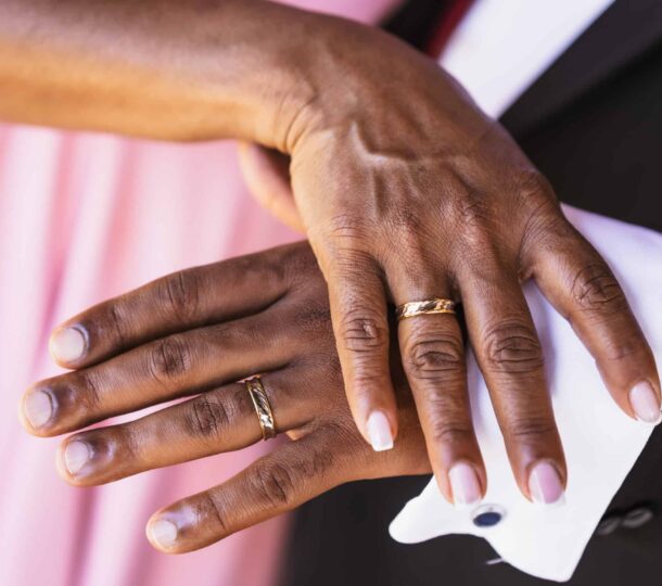 Black ethnic wedding couple showing rings at a wedding, marriage ceremony