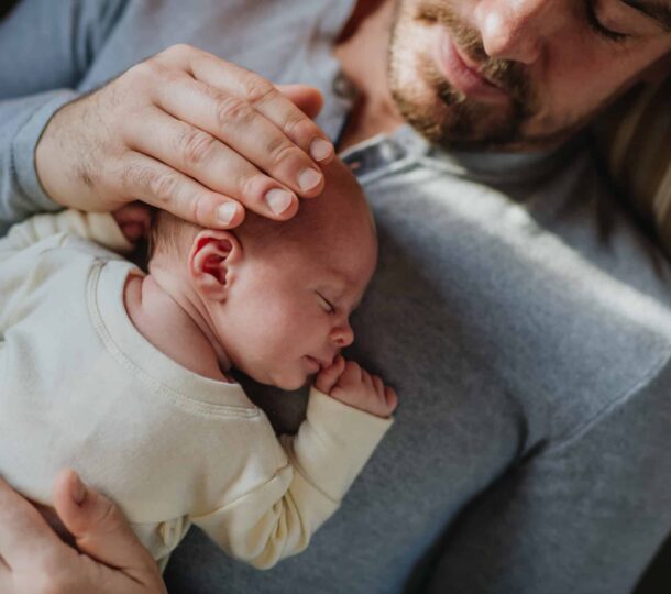 Close-up of father cuddling his little new born baby.